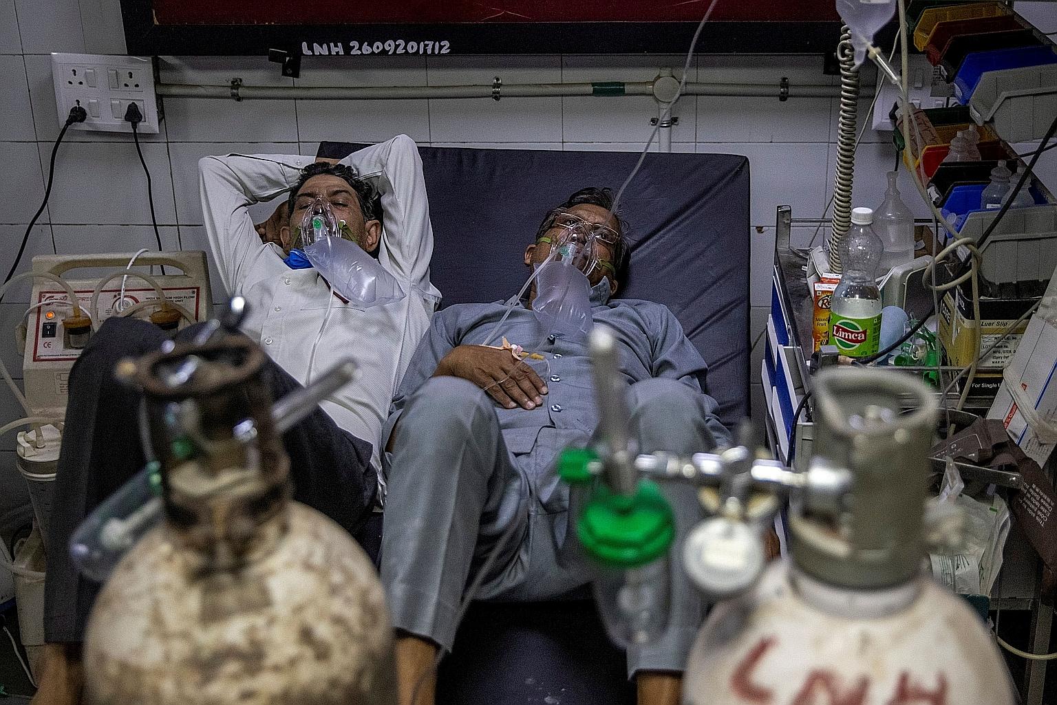 Two Covid-19 patients with oxygen masks sharing a bed in a ward in Lok Nayak Jai Prakash Narayan Hospital in New Delhi on Thursday. Hospitals in the country are struggling to cope amid an overwhelming number of Covid-19 patients.