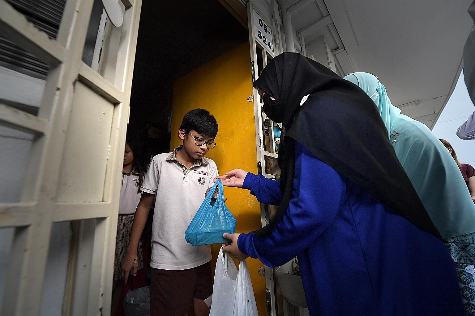 Volunteers distributing porridge to needy families in Jalan Kukoh yesterday. A total of 100 families received packs of porridge. ST PHOTO: ALPHONSUS CHERN