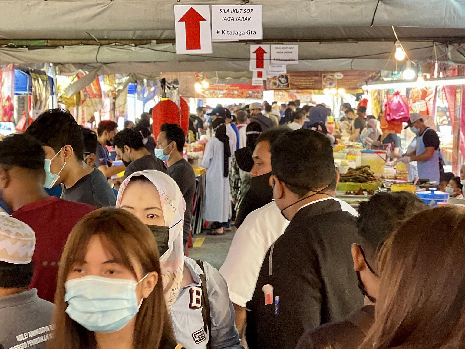 Visitors to the Kampung Pandan bazaar in Kuala Lumpur yesterday browsing under signs reminding them to socially distance. Malaysia's Covid-19 cases have resumed an upward trend in recent days, sparking fears that these bazaars could lead to another h