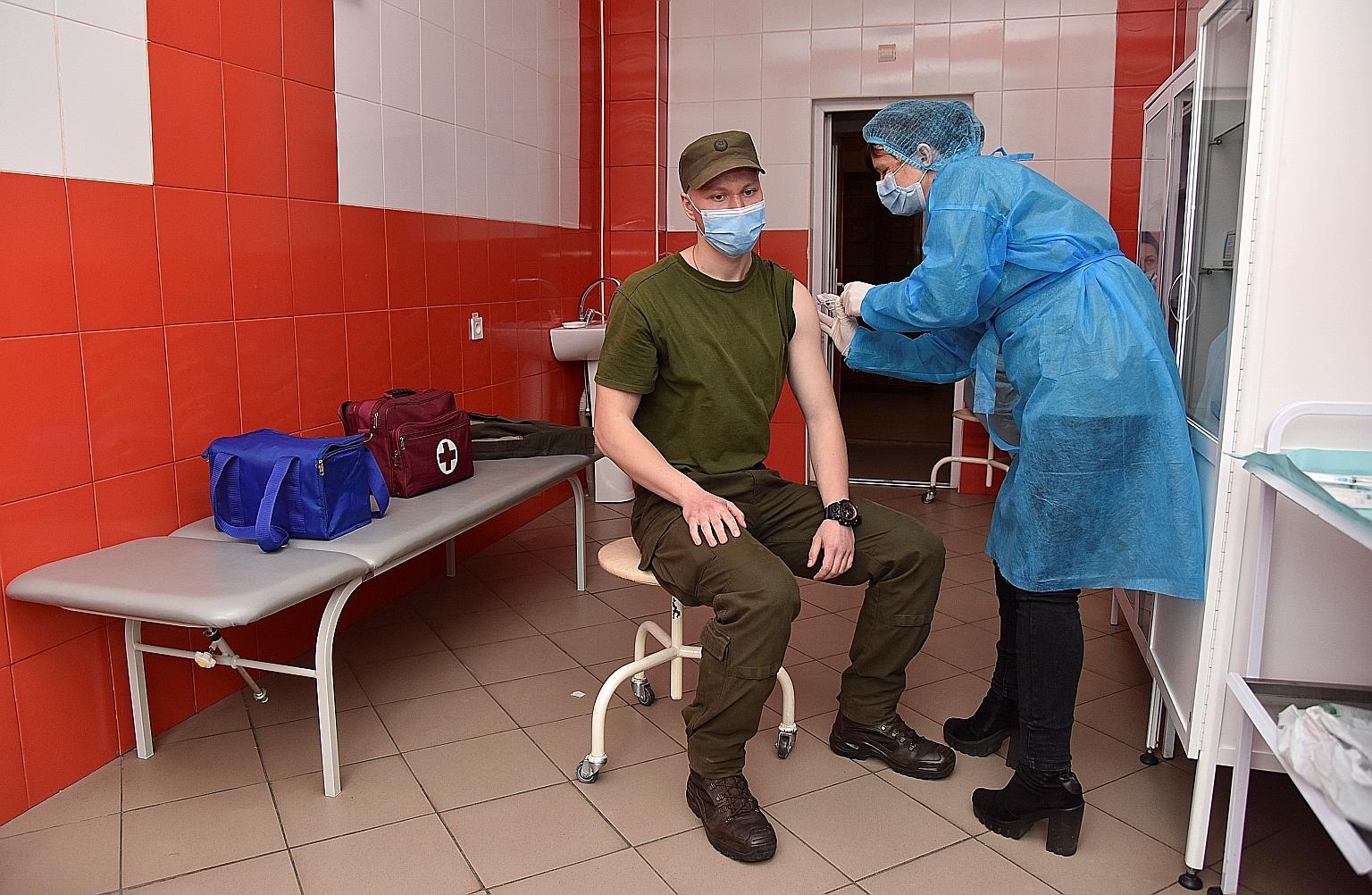 A Ukrainian National Guard soldier receiving an AstraZeneca shot in Lviv last Wednesday. The health situation in Ukraine is becoming more urgent: Daily new cases hit a record of more than 20,000 this month.