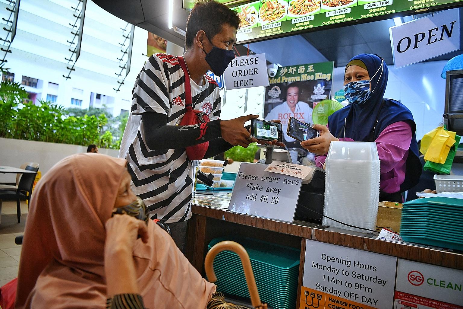 Madam Salmah Ahmat and her son Muhammad Azaman at Kampung Admiralty Hawker Centre to collect their food yesterday. A scheme set up in 2016 to distribute free briyani meals at a Housing Board block to Woodlands residents during the Ramadan fasting mon