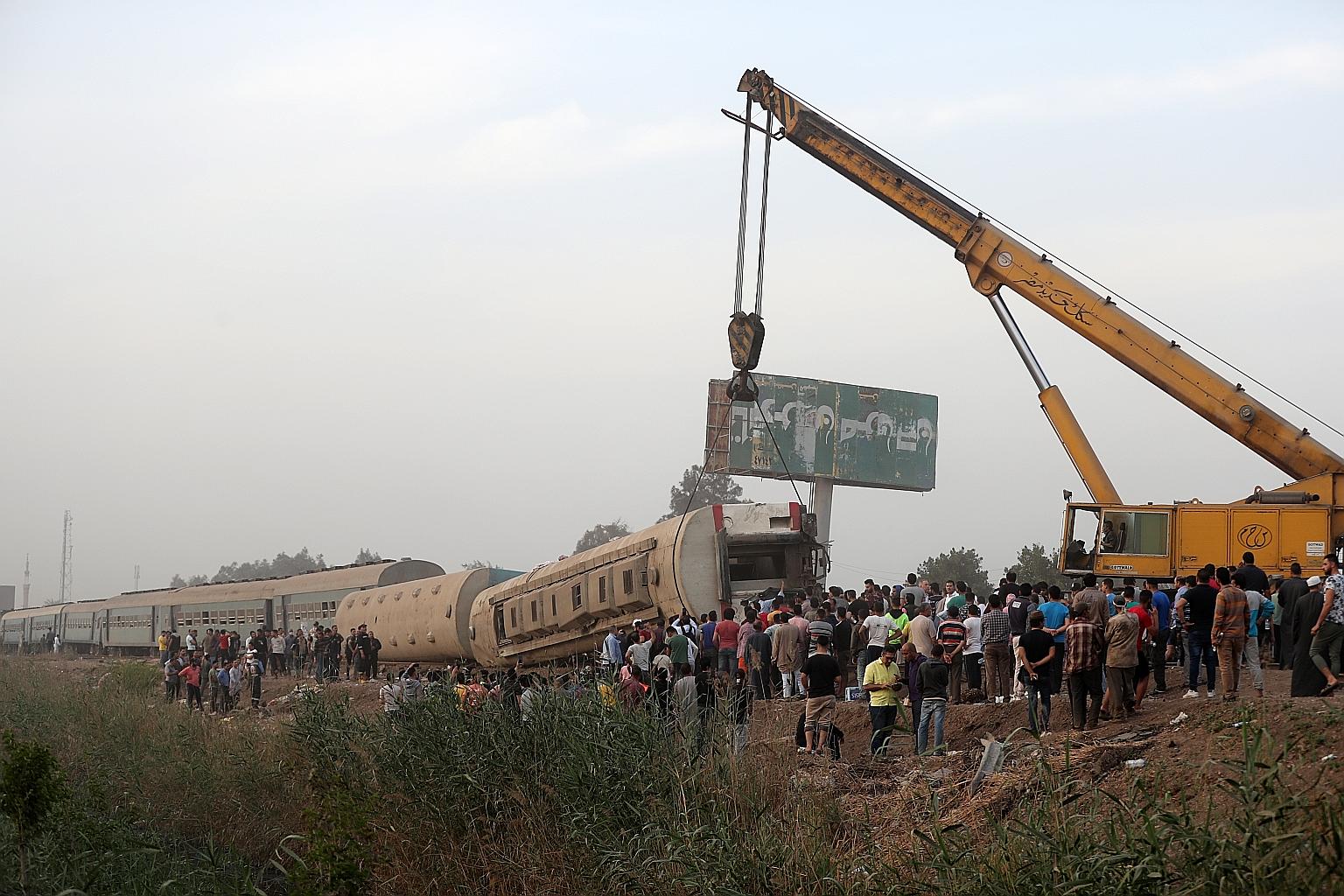 A damaged carriage of a passenger train that was derailed being lifted in Egypt's Qalioubia province, about 40km north of Cairo, on Sunday.