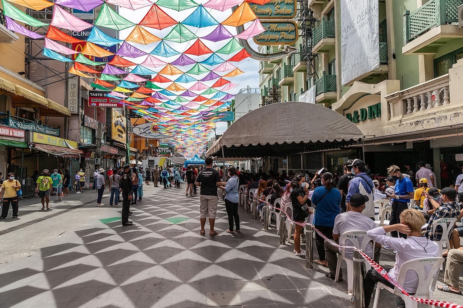 Healthcare workers directing people yesterday at a temporary Covid-19 testing site set up in Bangkok's Khaosan Road. Of the 14,736 new cases that Thailand has reported this month, 3,615 have been in Bangkok, the outbreak epicentre, and 146 medical st