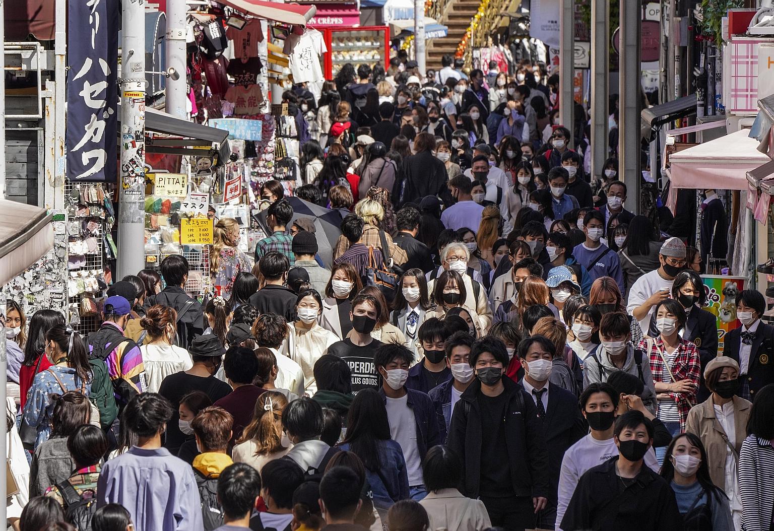Crowds thronging Tokyo's Harajuku area on Sunday. Despite current measures that include calling on bars and eateries to close early, commuter trains are packed, while crowds flock to stores and restaurants.