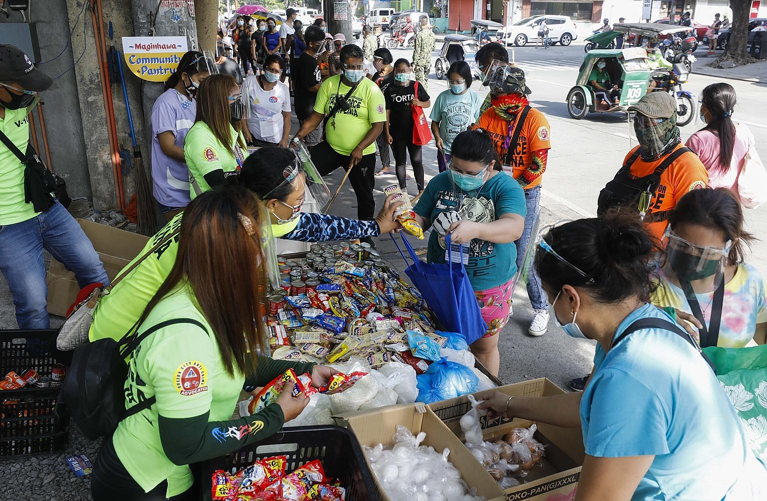 Filipinos hit hard by the pandemic queueing for free food items from a community pantry in Maginhawa Street in Quezon City, Metro Manila, on Monday. However, the pioneering pantry was shut down yesterday after President Rodrigo Duterte's supporters a