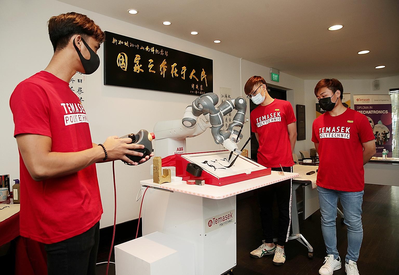 Temasek Polytechnic Mechatronic Engineering students Elfiqri Ashriq, 21, Xavier Teng, 21, Nicholas Yeo, 22, showcase a YuMi robot performing Chinese calligraphy at a preview session held at Sun Yat Sen Nanyang Memorial Hall yesterday.