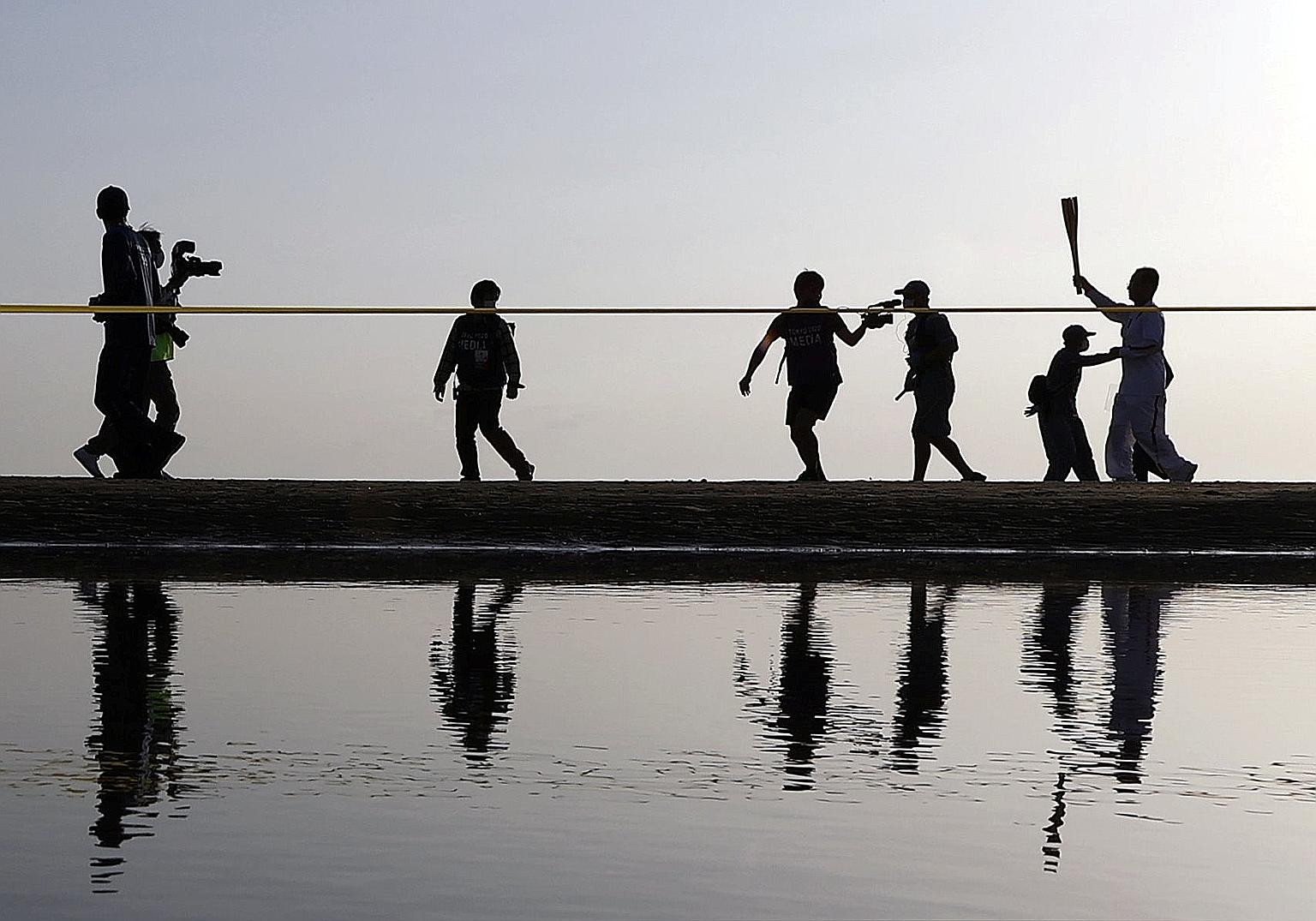 A Tokyo 2020 Olympic torch relay participant running on a beach in Mitoyo in Kagawa prefecture on the western island of Shikoku last Sunday. Some places have scrapped the relay over rising Covid-19 cases.