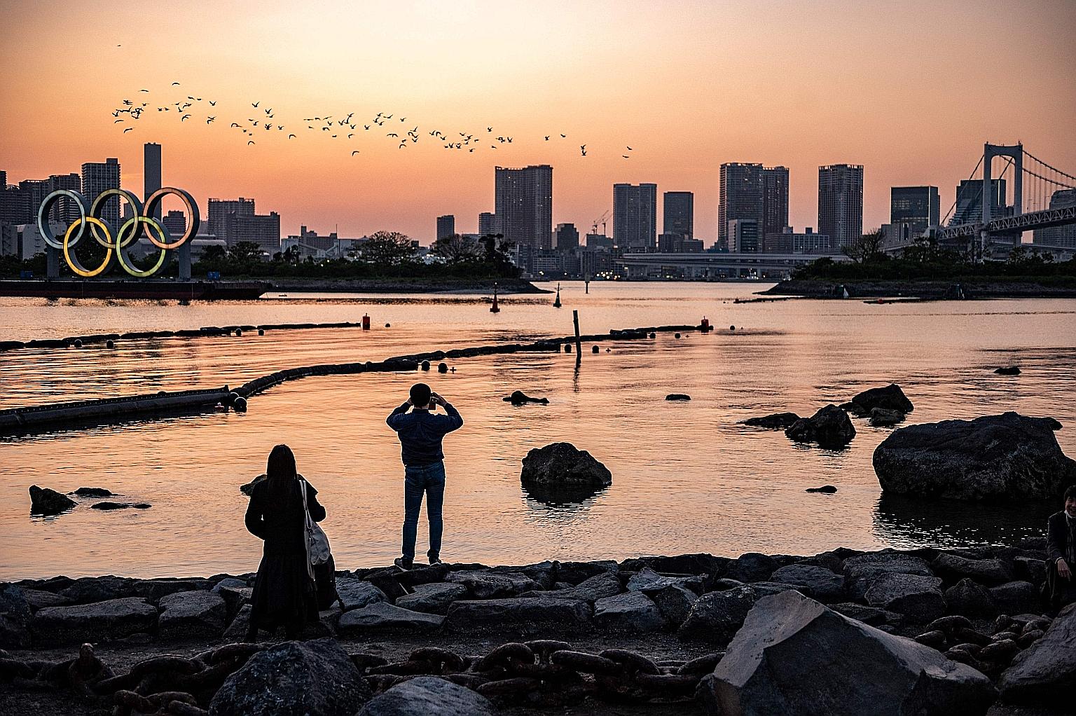 People watching the lighting up of the Olympic rings at the waterfront in Odaiba, Tokyo, on April 20. The latest rise in Covid-19 infections across Japan has stoked alarm, coming just three months before the planned start of the Tokyo Olympics and am