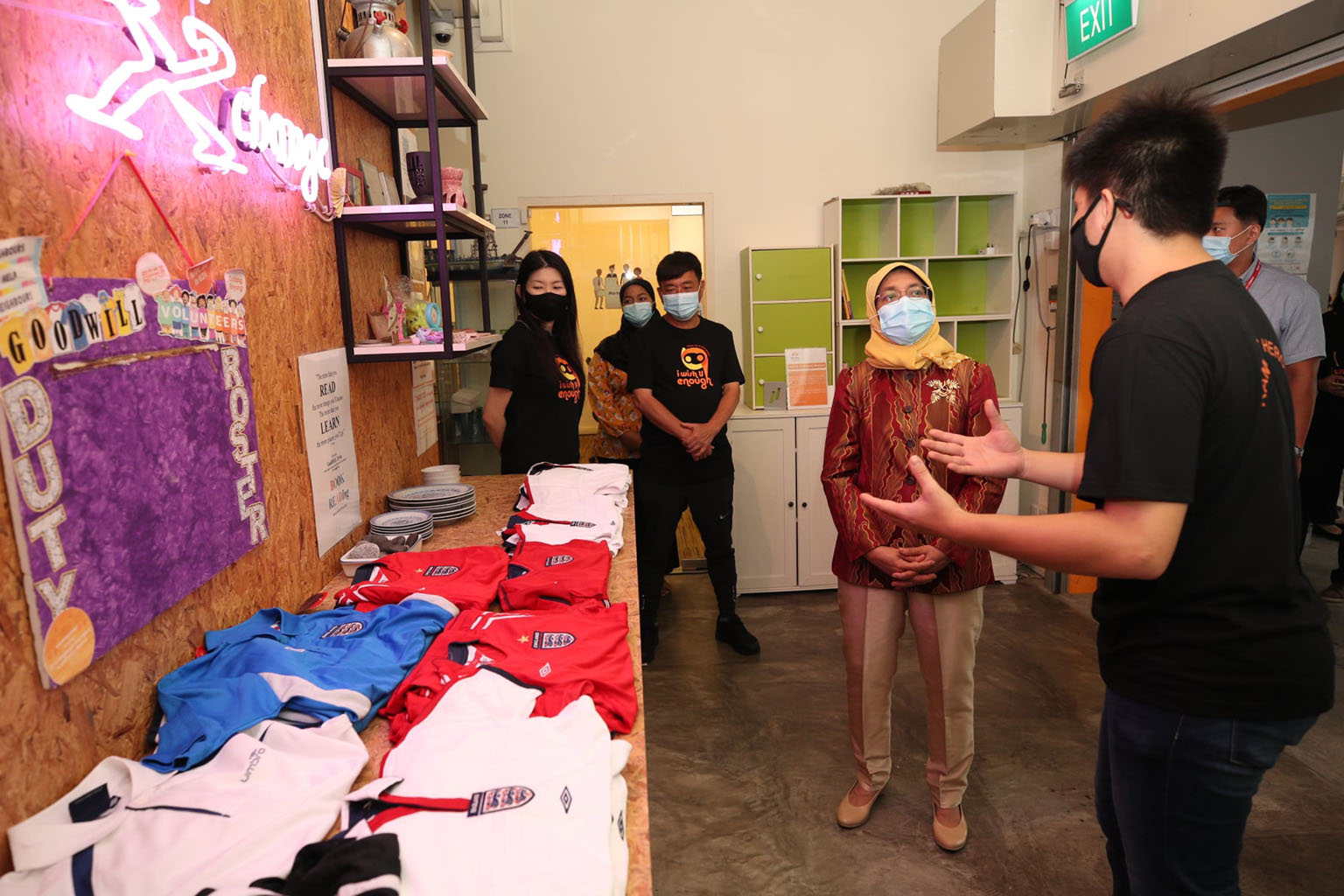 President Halimah Yacob with a South Central Community Family Service Centre volunteer who shared details about a Goodwill Exchange corner - which promotes the giving and receiving of used items - at its Bukit Merah premises during her visit yesterda
