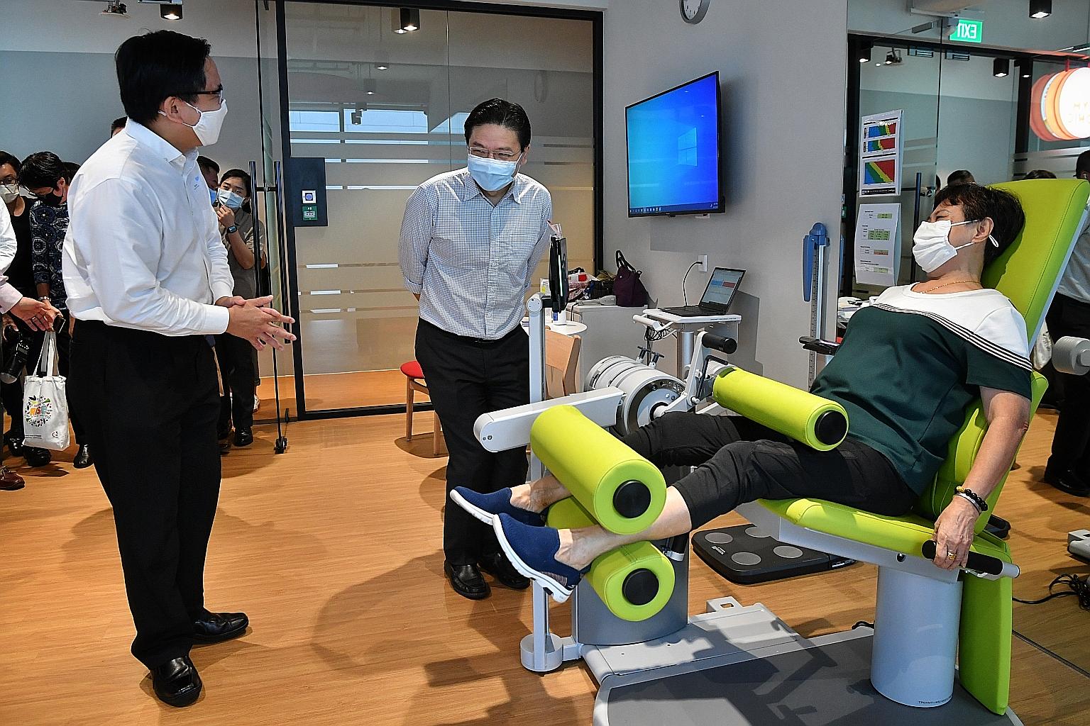 Education Minister Lawrence Wong (centre), an MP for Marsiling-Yew Tee GRC, chatting with Mayor of North West District Alex Yam, also an MP for the GRC, and a resident who was exercising at Gym Tonic at Space @ Woods Square yesterday. The gym is run 
