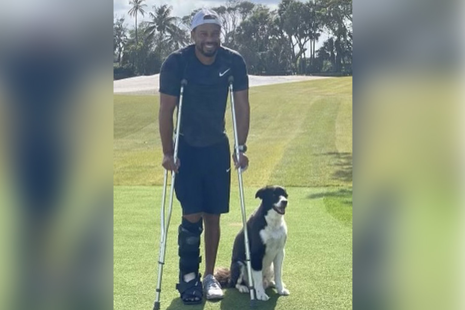 A smiling Tiger Woods on crutches, two months after his horrific car accident. He is with Bugs, a Border Collie-Springer Spaniel mix, at his home practice facility in Jupiter, Florida.