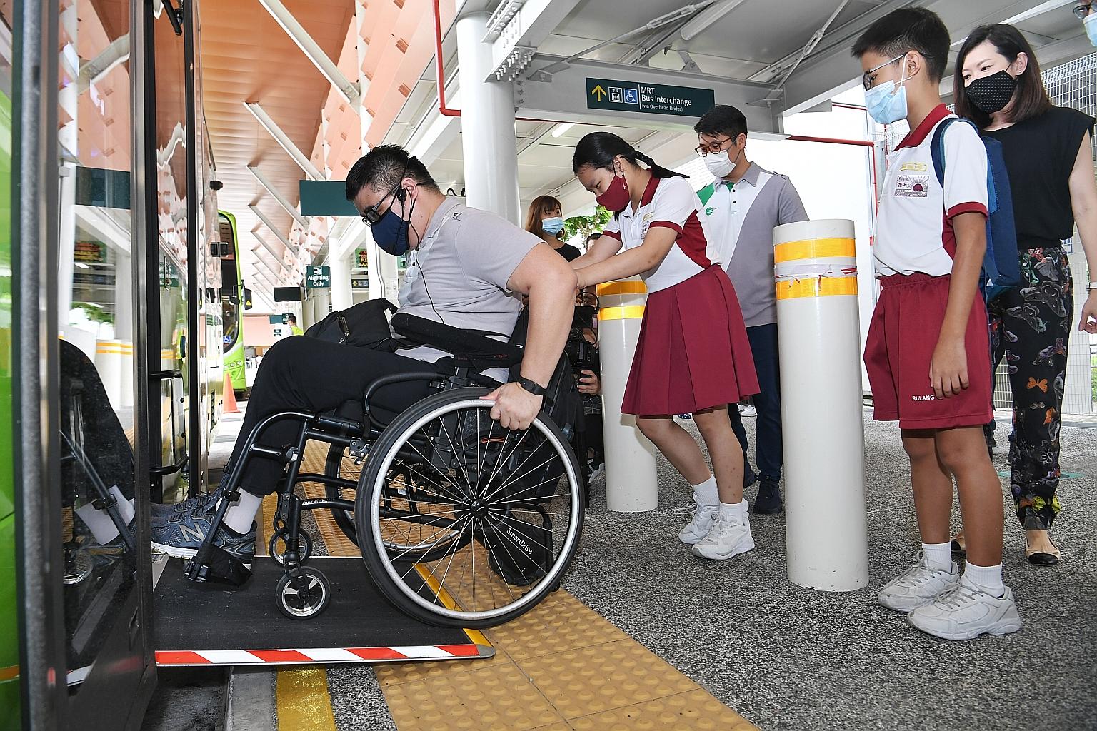 Reanne Leck, a Primary 5 pupil from Rulang Primary School, helping Tower Transit Singapore's inclusivity officer Kishon Chong to board the bus during the first session of the Public Bus Inclusivity Course at the Jurong East Bus Interchange on Saturda