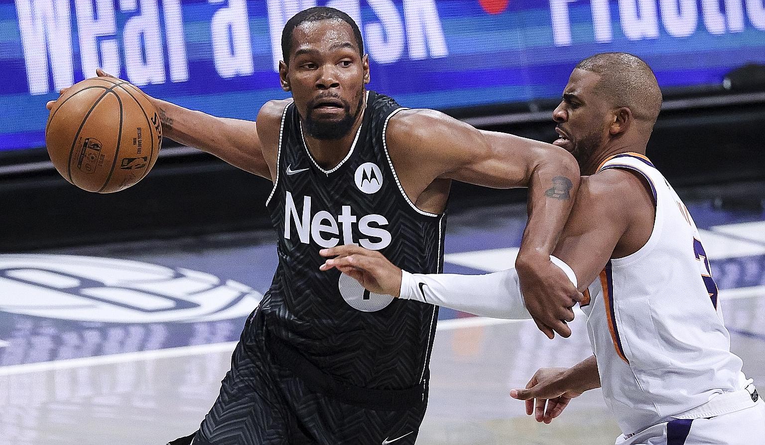 The Nets' Kevin Durant trying to drive past the Suns' Chris Paul in their NBA game at Barclays Centre in New York on Sunday. The forward returned after three games out with a thigh injury and the Nets won 128-119 to strengthen their hold on top spot