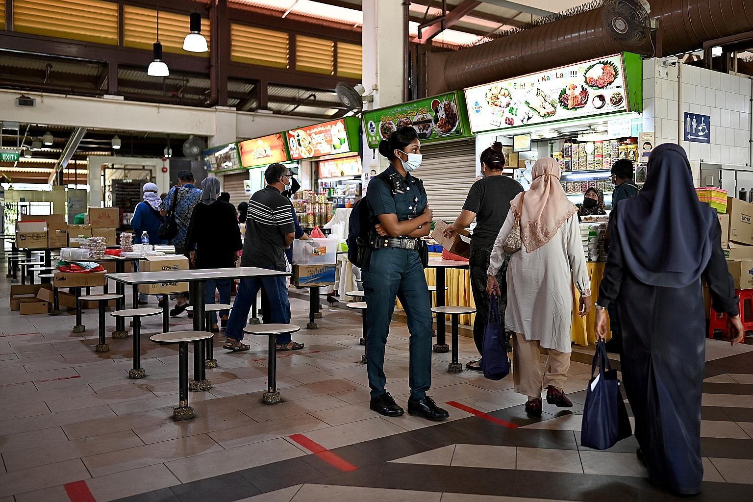 Security personnel patrolling the Geylang Serai Market food centre yesterday. More officers are being deployed at Tekka and Geylang Serai markets to enforce safe distancing ahead of Hari Raya Puasa.