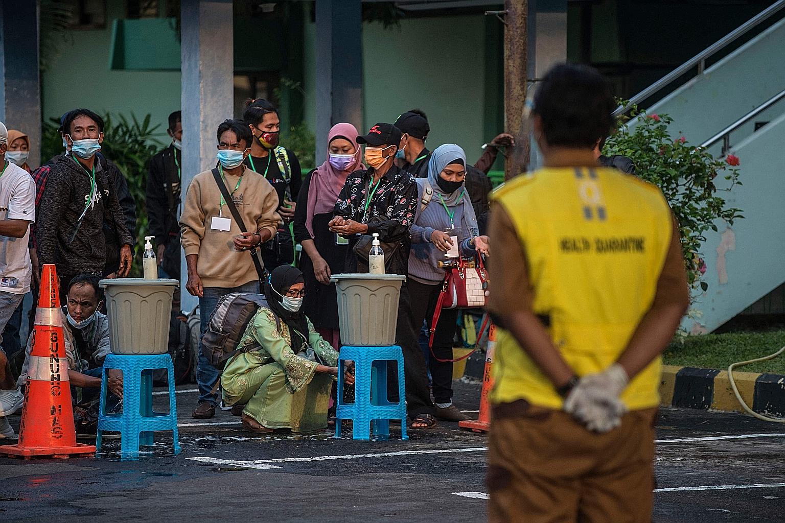 Migrant workers arriving back in Indonesia from Malaysia and Singapore awaiting Covid-19 screening in Surabaya on Wednesday before they are quarantined. President Joko Widodo said daily new Covid-19 cases almost doubled following last year's Hari Ray