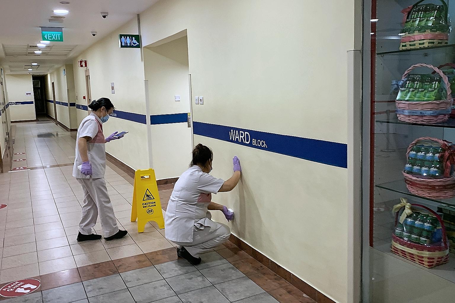 Cleaners disinfecting a wall near the visitor registration counter at Tan Tock Seng Hospital yesterday. The hospital has emerged as a Covid-19 cluster, and measures have been put in place to stem the spread. ST PHOTO: KEVIN LIM