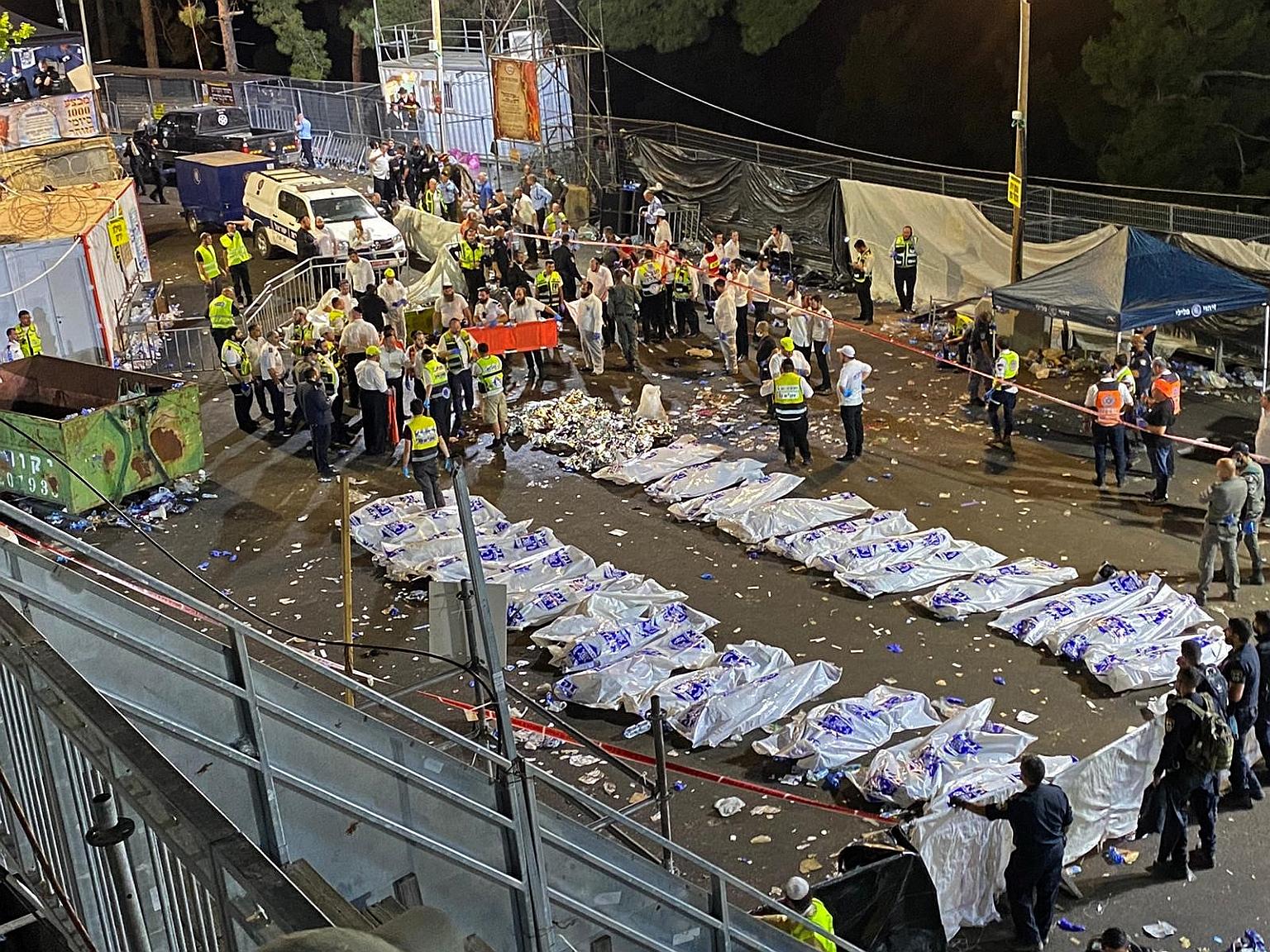 Israeli security officials and rescuers gathering near the body bags of victims who died in a stampede during a packed religious gathering in Meron yesterday. PHOTO: AGENCE FRANCE-PRESSE