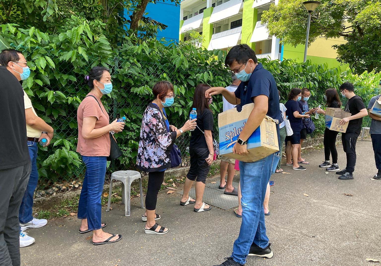 Bottled water being given to those queueing for Covid-19 tests at the former Da Qiao Primary School in Ang Mo Kio yesterday. By 11am, there were over 300 people in a line stretching 300m away from the facility.