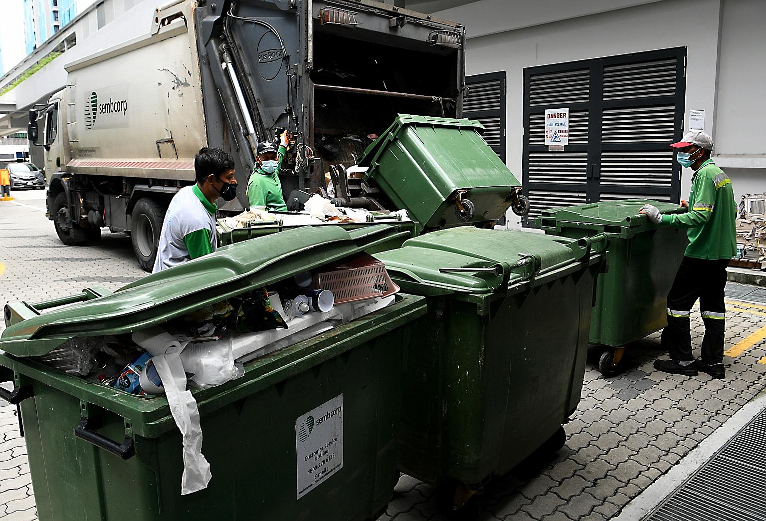 Above: Workers carrying out manual waste collection at Alkaff CourtView in Bidadari estate on Saturday. It is temporarily back to manual rubbish collection at the BTO project after residents complained about foul smells from a choked waste system and