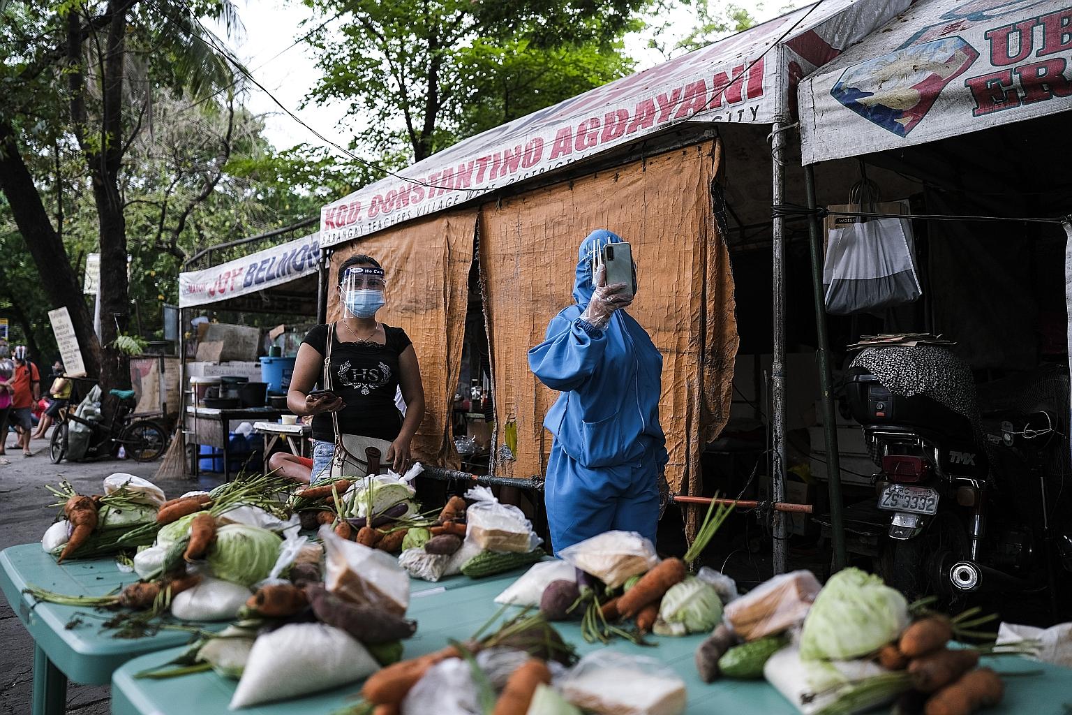A health safety official checking vegetables donated by farmers in Manila yesterday. The Philippines - where officials in the capital have banned all non-essential movement - halved the rate of contraction of its gross domestic product to 4.2 per cen