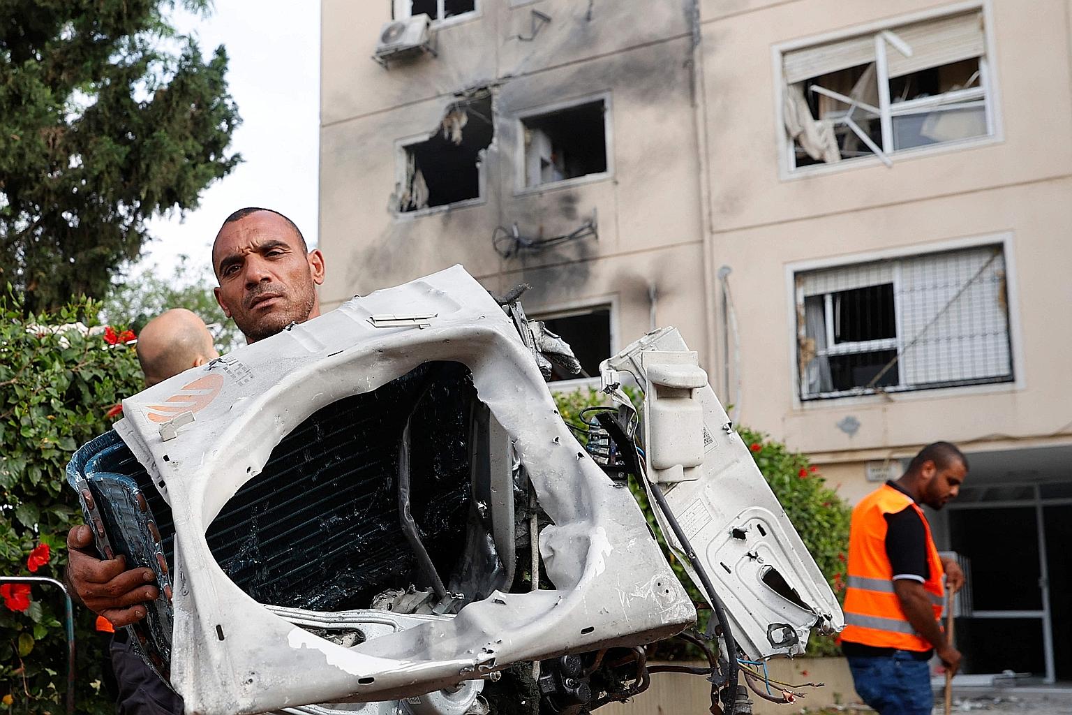 An Israeli with parts of a damaged car outside a building in Ashkelon yesterday, following rocket fire from Hamas.