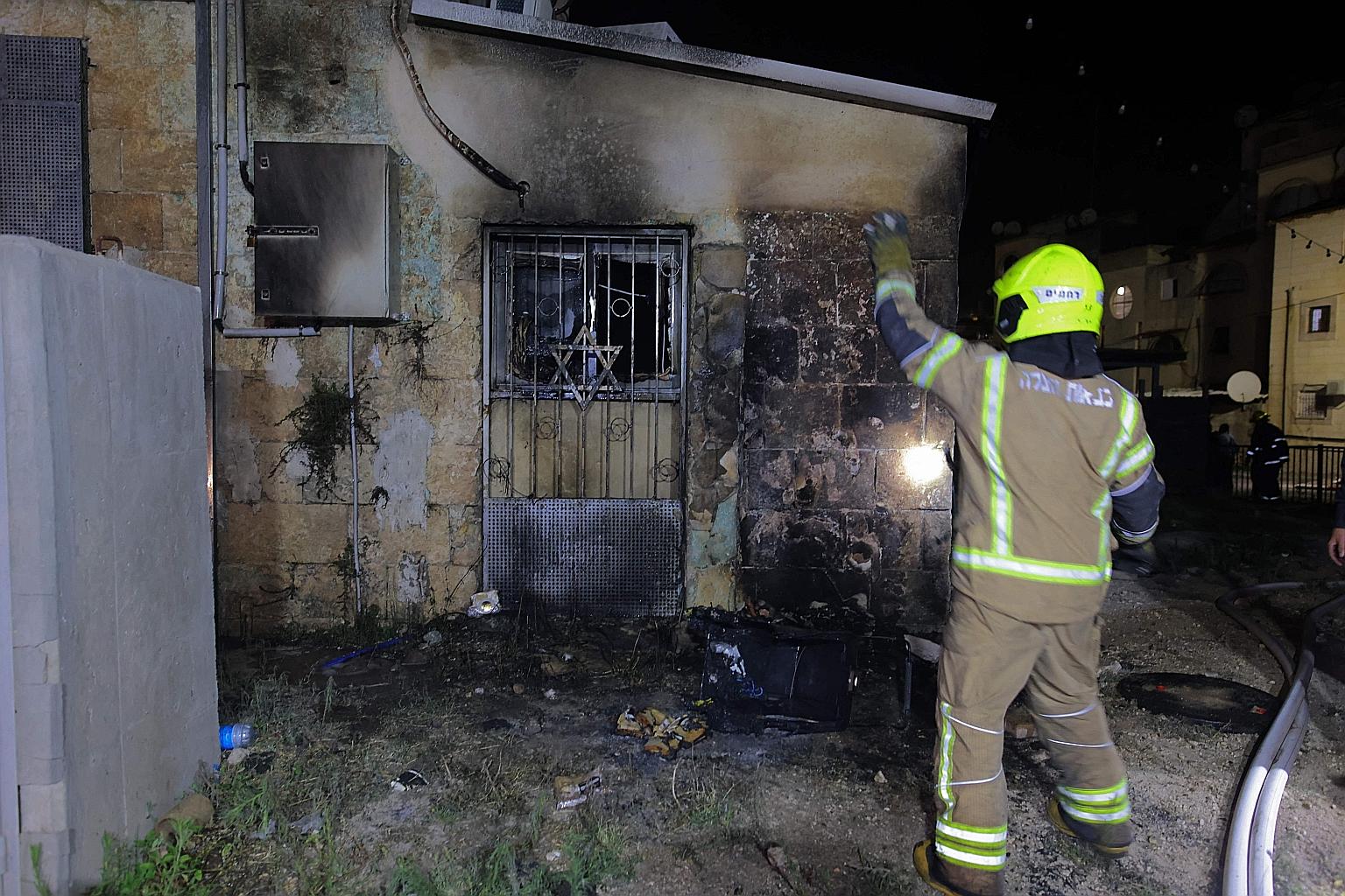 An Israeli firefighter inspecting a synagogue after it was set on fire by Arab Israelis in the mixed Arab-Jewish city of Lod in Israel yesterday. Angry Arab youths rioted this week after police violence in Jerusalem spilt over into conflict with the 
