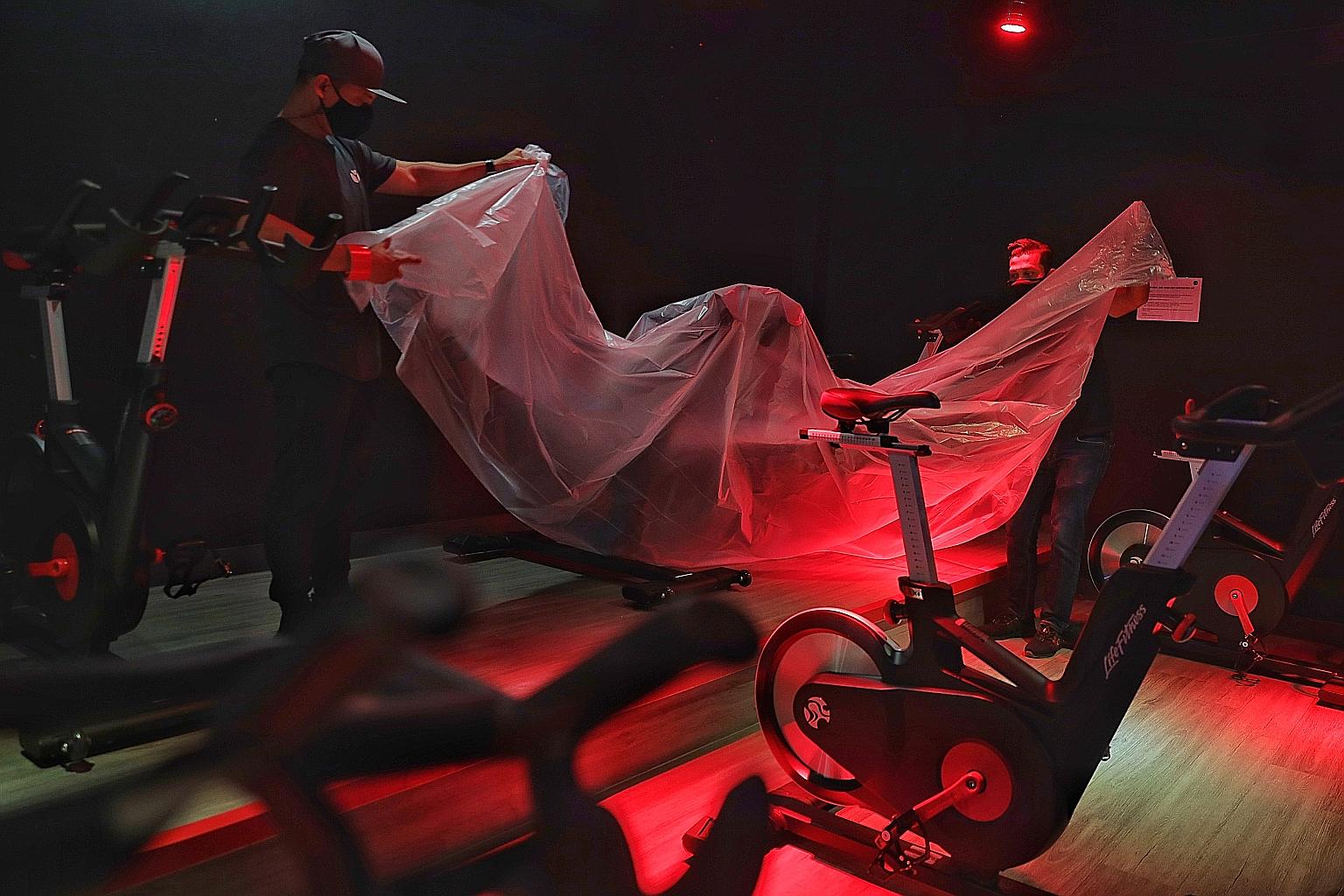 Staff covering up stationary bicycles at a True Fitness gym on May 7, the last day before the reintroduction of phase two measures. Under new guidelines, indoor facilities can offer only low-intensity activities.