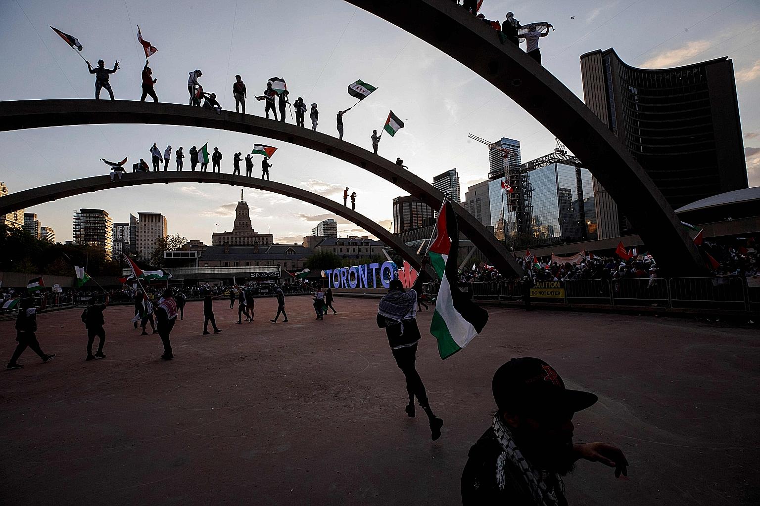 Demonstrators waving flags atop the arches of Toronto City Hall as thousands gathered in the Canadian city on Saturday to show their support for the people of Palestine.