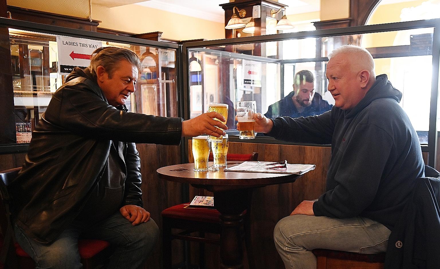 Customers raising a pint in London yesterday as pubs, restaurants and cafes across most of Britain resumed full indoor services.