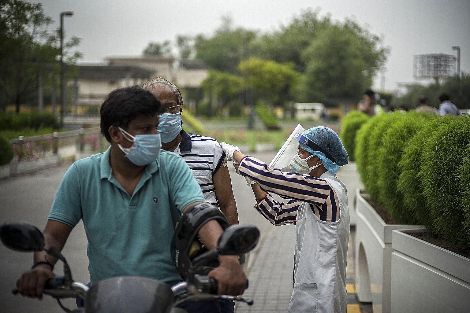 A motorbike passenger getting his jab at a drive-through vaccination site in Noida, Uttar Pradesh, on Monday.