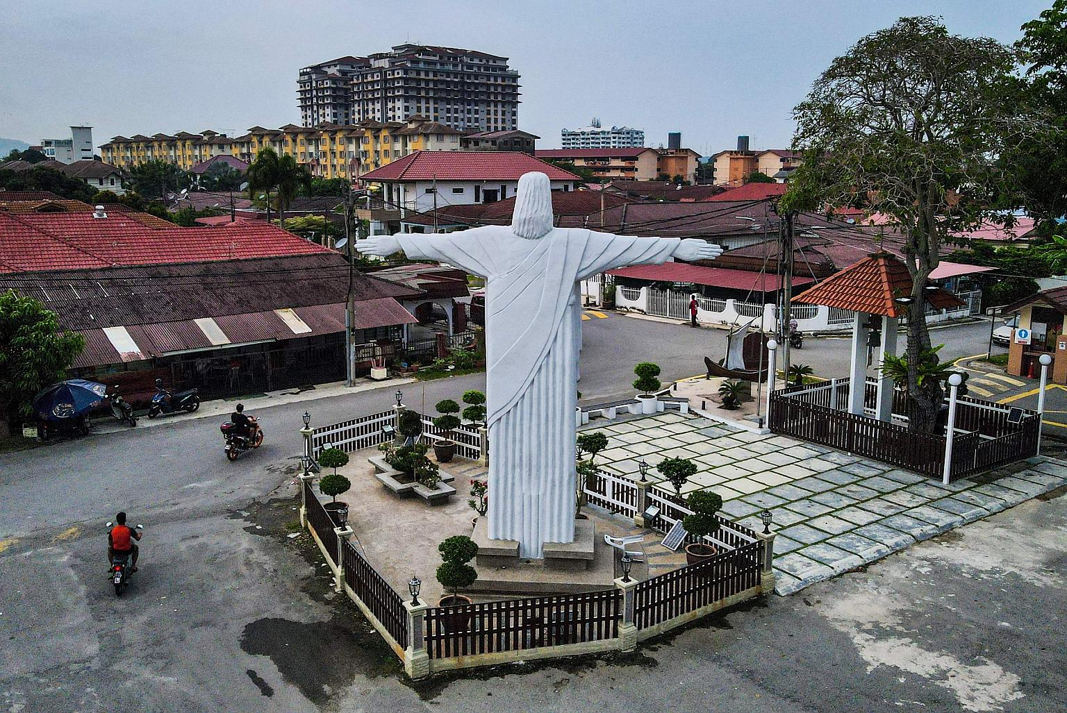 Two motorcyclists passing the quiet streets of the Portuguese Settlement, where a replica of the Christ the Redeemer statue stands, in Malacca yesterday, during a nationwide lockdown. Malaysia yesterday reported 6,493 new cases of Covid-19 and 50 fat