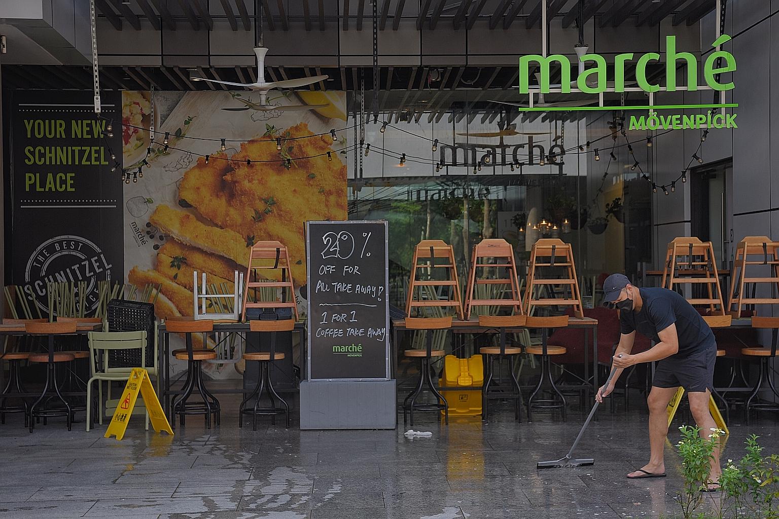 An employee of Marche at Jem cleaning the restaurant yesterday. Shoppers were turned away from Jem and Westgate yesterday, but tenants were allowed into the malls. Workers were also seen disinfecting common touchpoints such as directory panels.