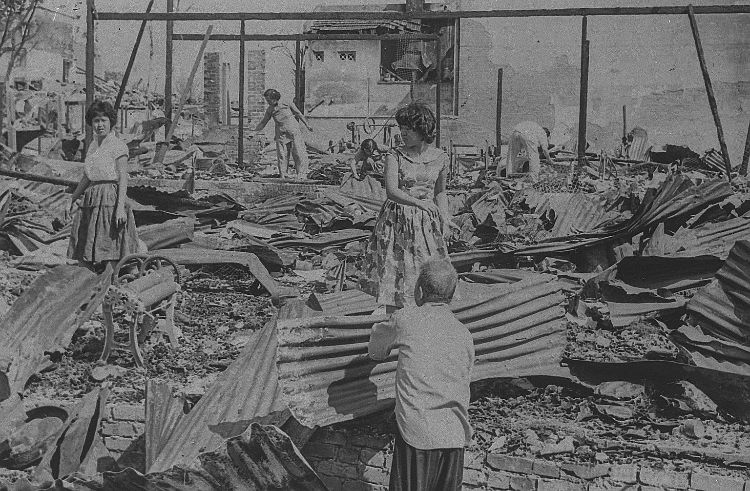 Former residents surveying the ruins of their homes in the aftermath of the fire. Within nine months of the blaze, all the victims were rehoused in flats. The opening in September 1961 of five HDB blocks with 904 one-room, semi-communal units, all of