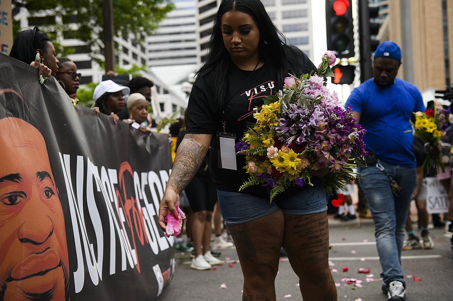 A woman spreading flower petals before a march in honour of Mr George Floyd on Sunday in Minneapolis. Mr Floyd was killed on May 25 last year by a police officer, who knelt on his neck for over nine minutes.
