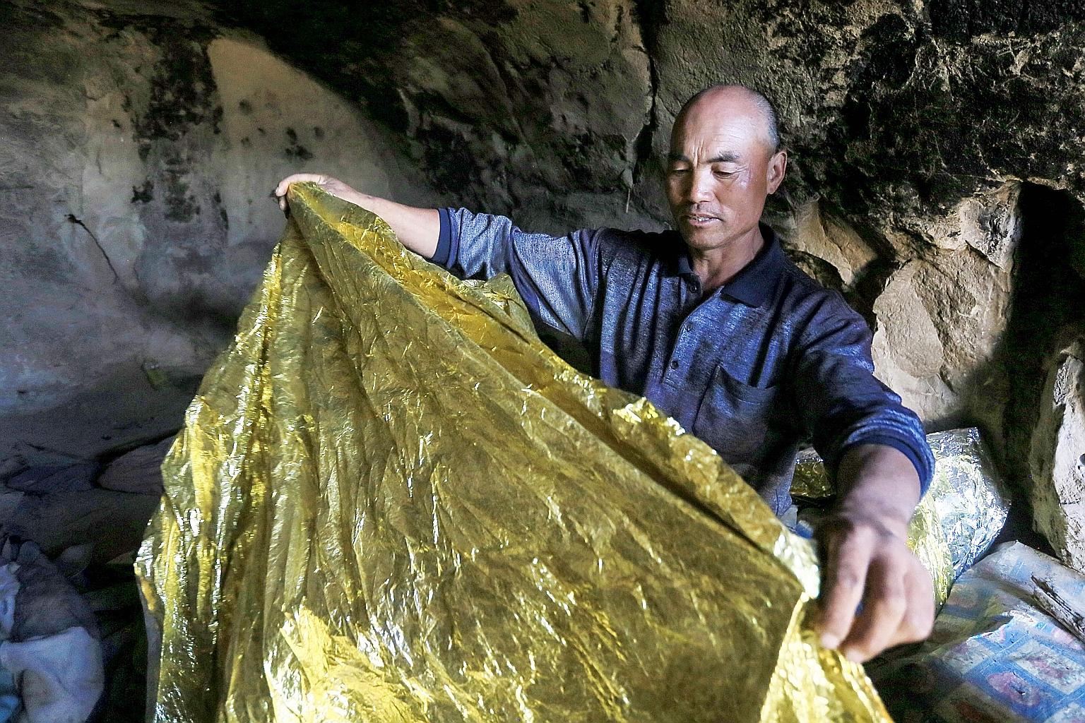 Shepherd Zhu Keming showing a thermal insulation blanket in the cave where he sheltered the stricken athletes near the city of Baiyin, in China's north-western Gansu province. He regretted that he was unable to do more to help others who reportedly s