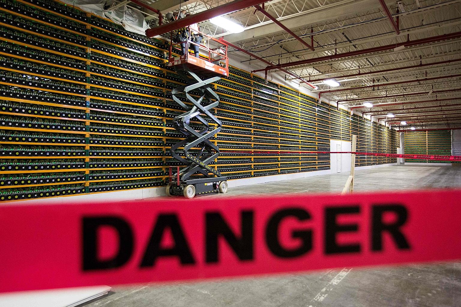 Two workers using an extendable lift along a wall of Bitcoin mining at Bitfarms in Saint Hyacinthe, Canada's Quebec province, in this file photograph taken on March 19, 2018. One observer in Singapore said cryptocurrencies are popular for use in illi