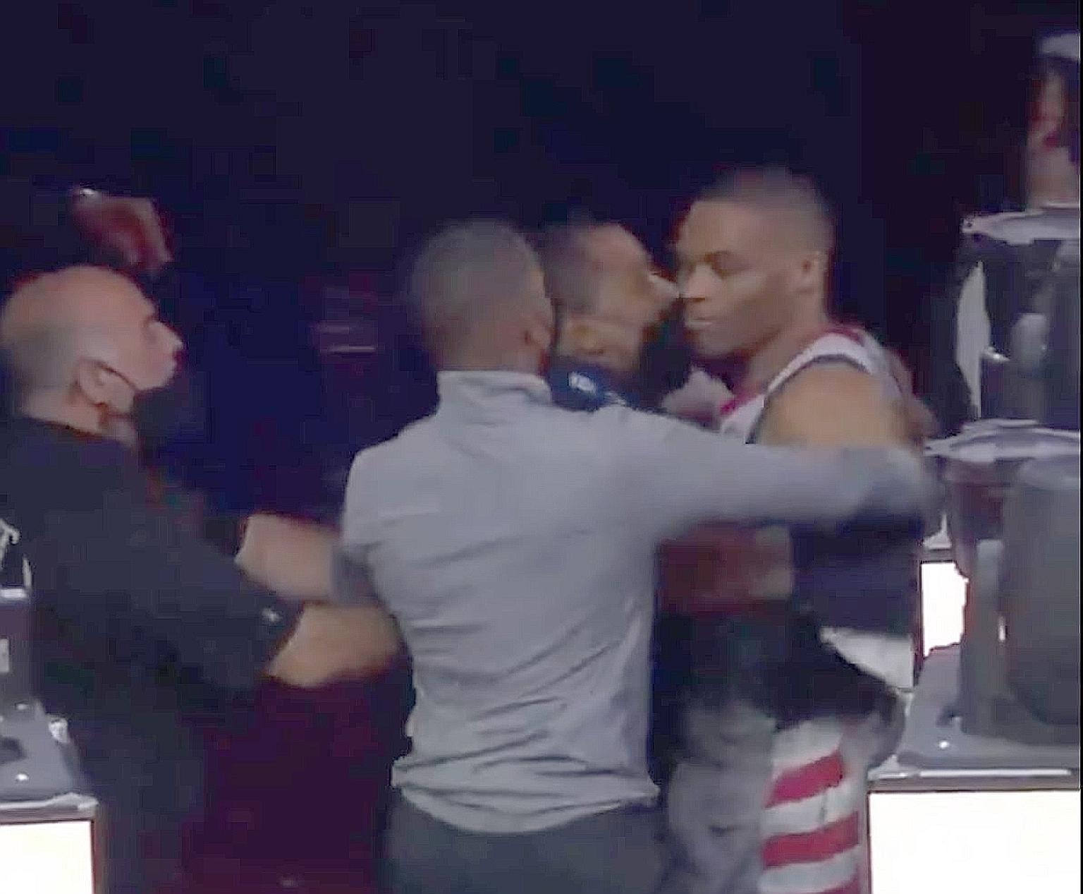 Wizards' Russell Westbrook being restrained by staff after a fan throws popcorn at the guard. PHOTO: TWITTER/ SPORTSCENTER