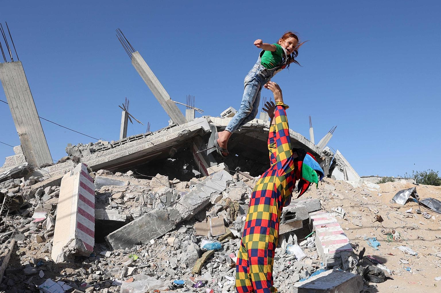 A Palestinian dressed as a clown entertains a child amid the ruins of a building destroyed during recent Israeli bombing in Rafah, in the southern Gaza Strip.