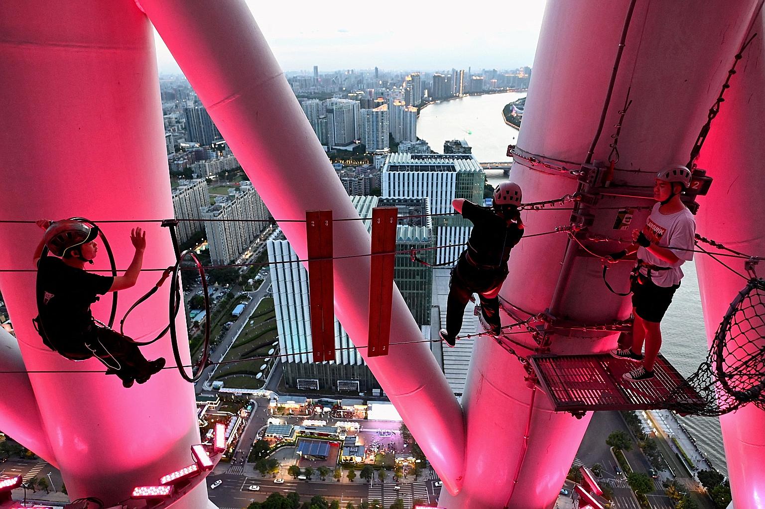 Tourists and their guide crossing a tightrope at the "Landmark Alpha" adventure park at the Canton Tower in Guangzhou, China, last week. The park offers extreme sports enthusiasts three different courses at heights ranging from 198m to 298m. PHOTO: A