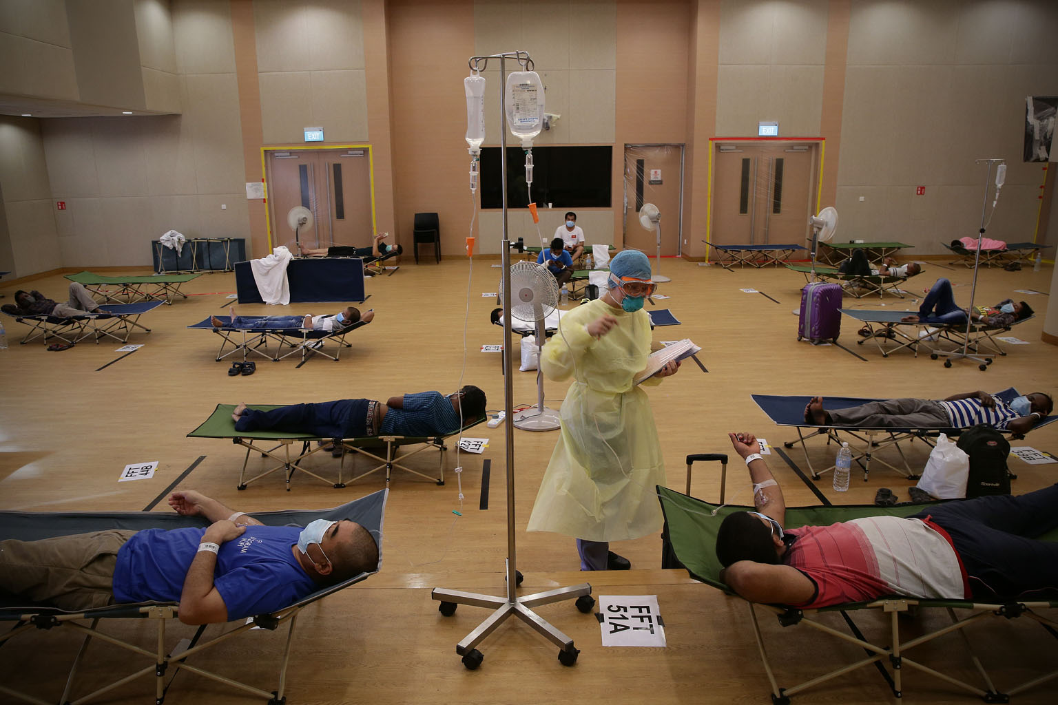 THE MEDICAL TEAMS A nurse at Jurong Community Hospital checking on a patient, and taking note of his vital signs, while patients awaited their Covid-19 swab test results. Medical personnel are bearing the brunt of the burden of the year-long battle a
