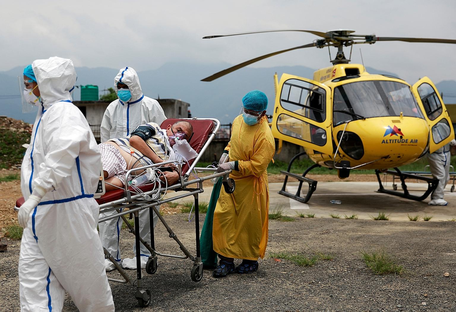 Workers transporting a Covid-19 patient after he was airlifted by helicopter from Pokhara to Kathmandu yesterday because of health complications. Nepal is now considering declaring a health emergency.