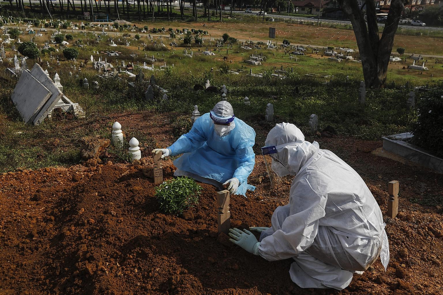 Two brothers at the grave of their father, who died of Covid-19, in Kuala Selangor, outside Kuala Lumpur, last Friday. Malaysia goes into a stringent two-week lockdown today to stem a third wave of Covid-19 infections, following record numbers of cas