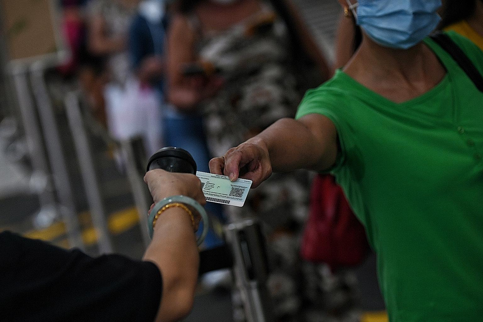 A foreign domestic worker getting her identification card scanned for entry to Lucky Plaza in April. Some maids had been released early from stay-home notice, only to test positive again a few weeks later, after they were called back for swab tests o