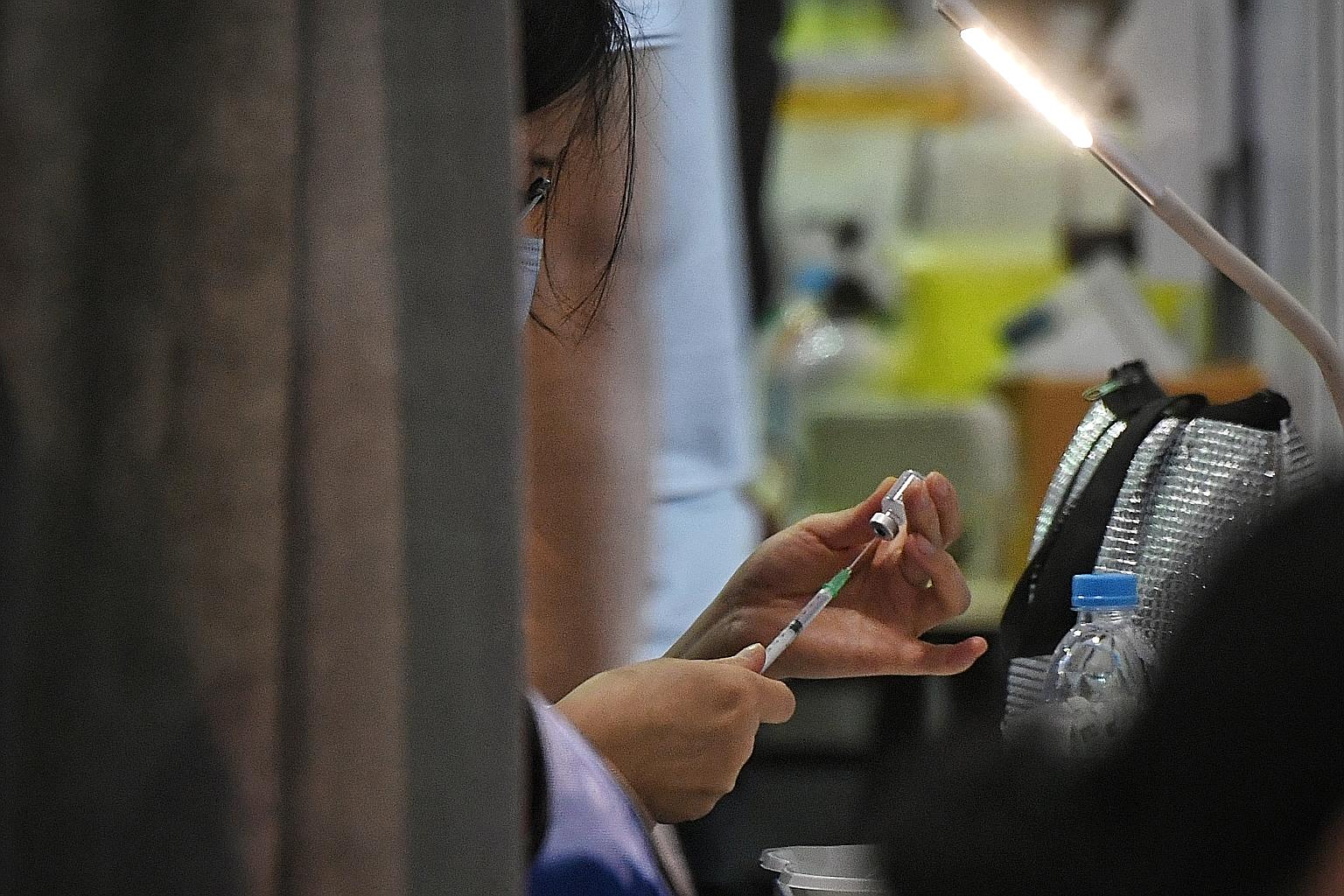 A medical worker drawing a dose of Covid-19 vaccine into a syringe. Booster jabs may be useful when the protective effects of vaccination wane, or if new virus variants are resistant to existing vaccines. ST PHOTO: KUA CHEE SIONG