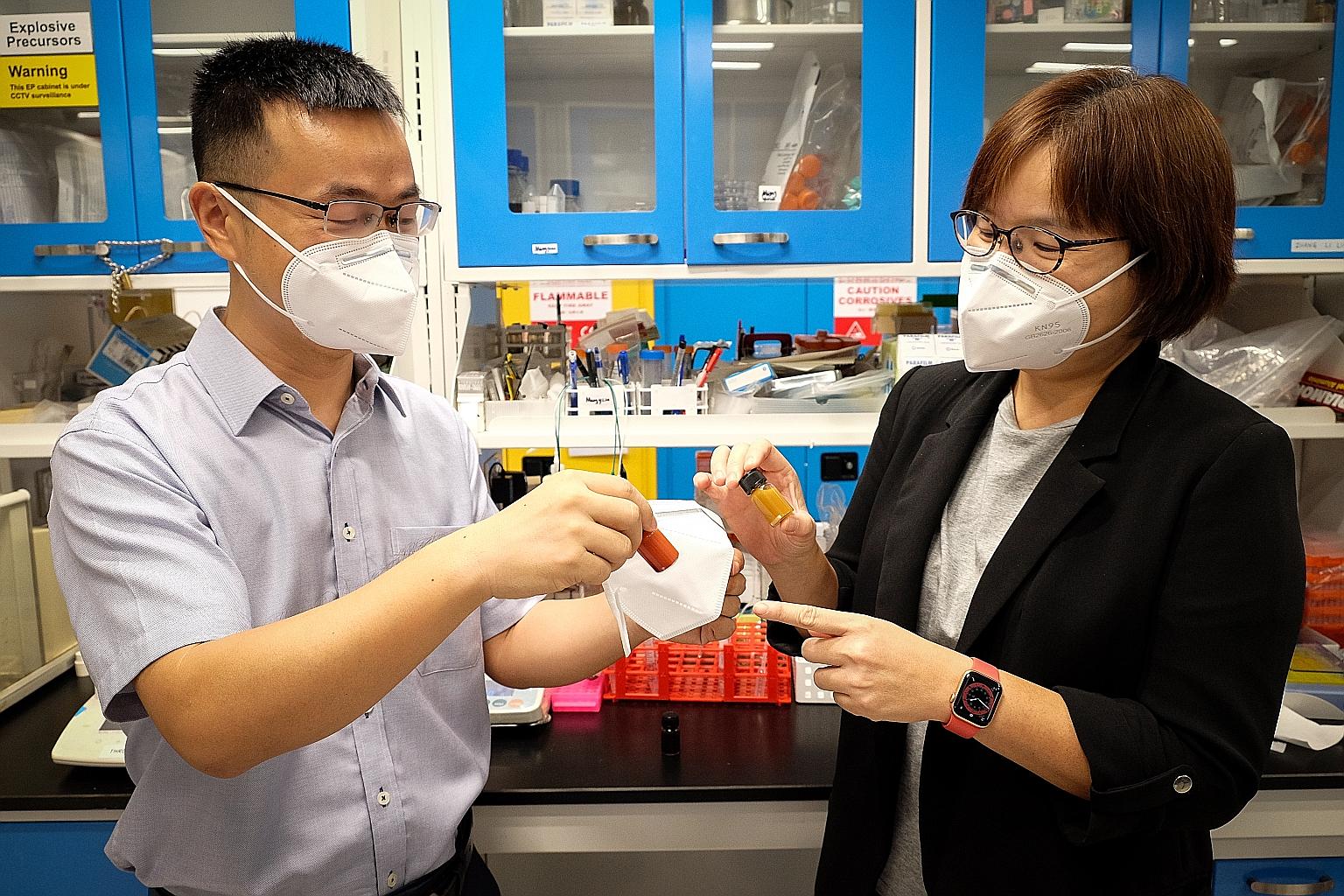 Associate Professor Liu Zheng (left) and Professor Lam Yeng Ming with the new mask and bottles of copper oxide nanoparticles - the mask is coated with a layer of copper oxide which can damage the DNA of key cell structures in bacteria.