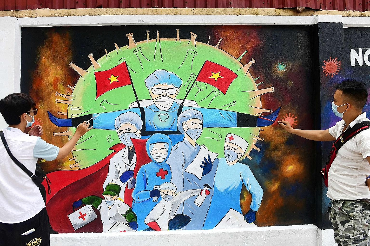 Vietnamese street artists painting a mural depicting front-line workers battling Covid-19 in a street in Hanoi yesterday. Vietnam, with a population of around 98 million, has recorded a total of 10,241 coronavirus cases, with 58 deaths, since the pan