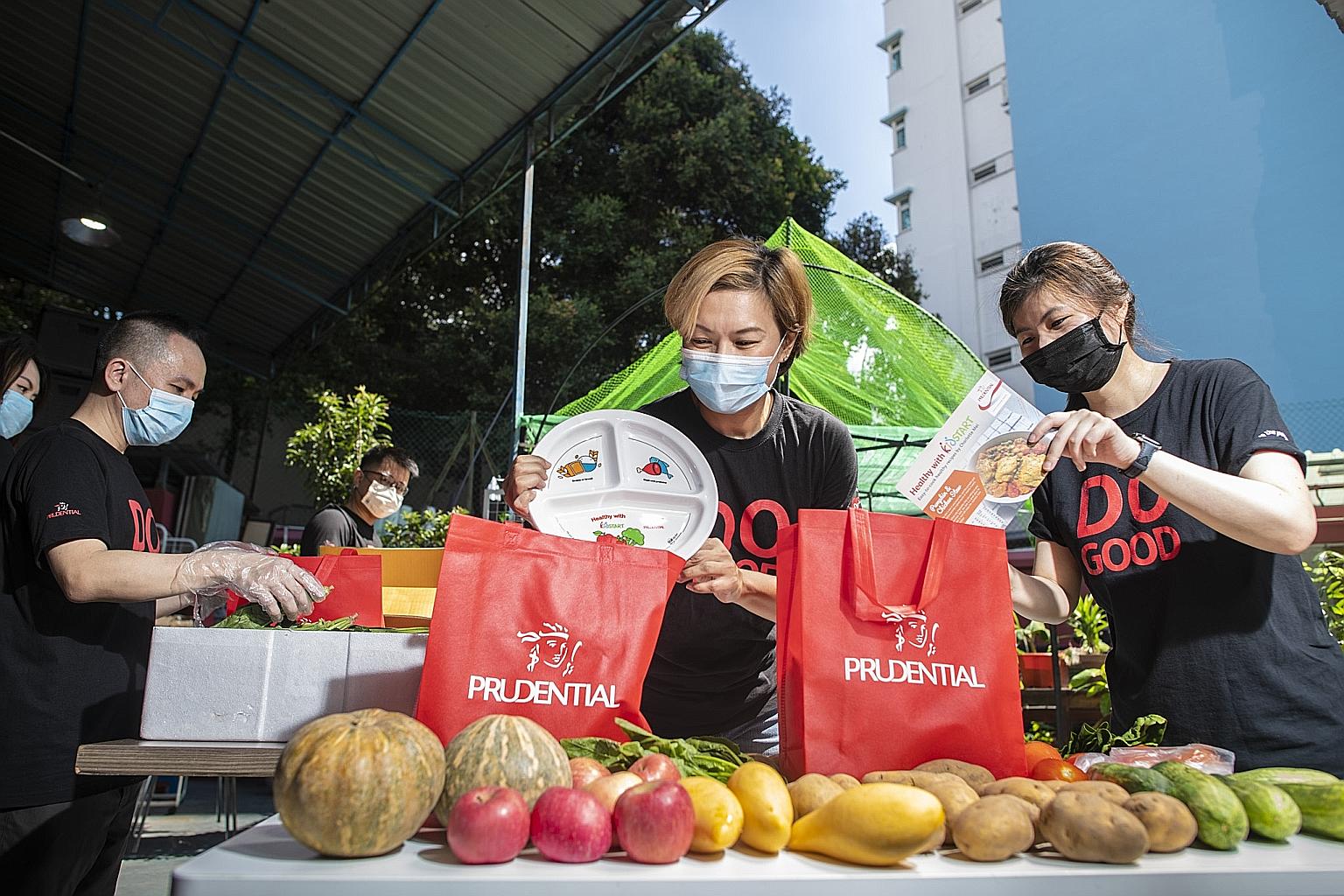 Prudential staff, including Ms Ariel Ong (centre), putting together healthy-eating packs containing fresh produce, a recipe card and a "Healthy Plate" showing ideal proportions of major food groups, before Singapore's phase two (heightened alert) Cov