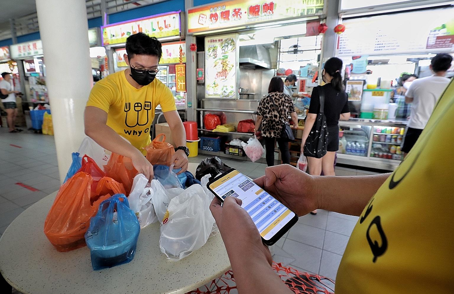 Staff of food delivery platform WhyQ organising orders placed on the app before handing them to delivery riders at Tiong Bahru Market and Food Centre on Tuesday. WhyQ is one of the partners in a work group formed to help hawkers by offering them educ