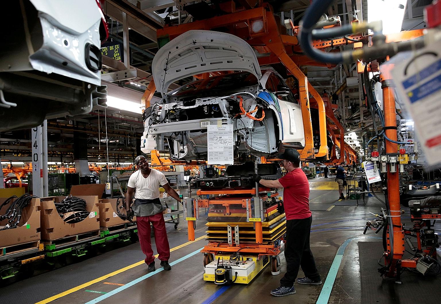 Workers with a partially assembled Chevrolet Bolt electric vehicle (EV) at a General Motors (GM) plant in Michigan in 2018. GM's current fleet still overwhelmingly consists of internal combustion engines, and the Chevy Bolt is the only EV model in sh