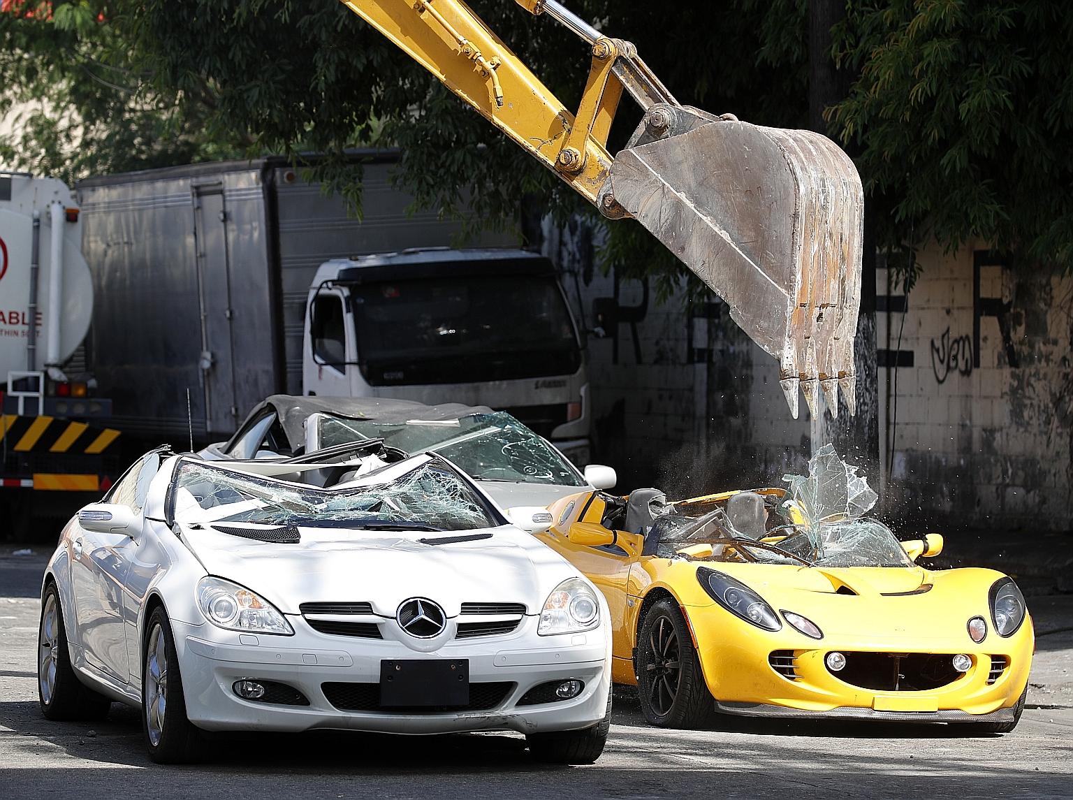 A backhoe destroying smuggled luxury cars at the Bureau of Customs in the Philippine capital of Manila on Thursday. It was the second time this year that the Philippine Bureau of Customs has demolished smuggled vehicles, with 21 cars worth an estimat